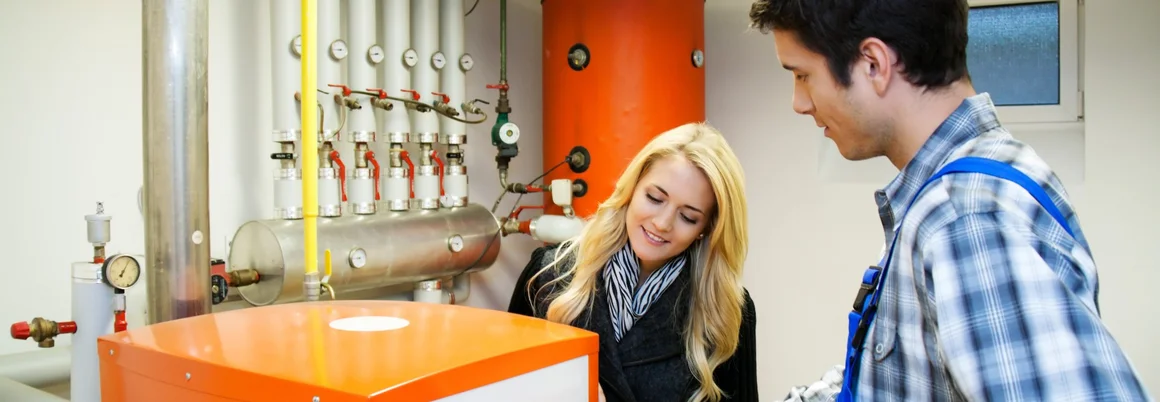 Ein Fachmann erklärt einer Kundin eine Heizung.